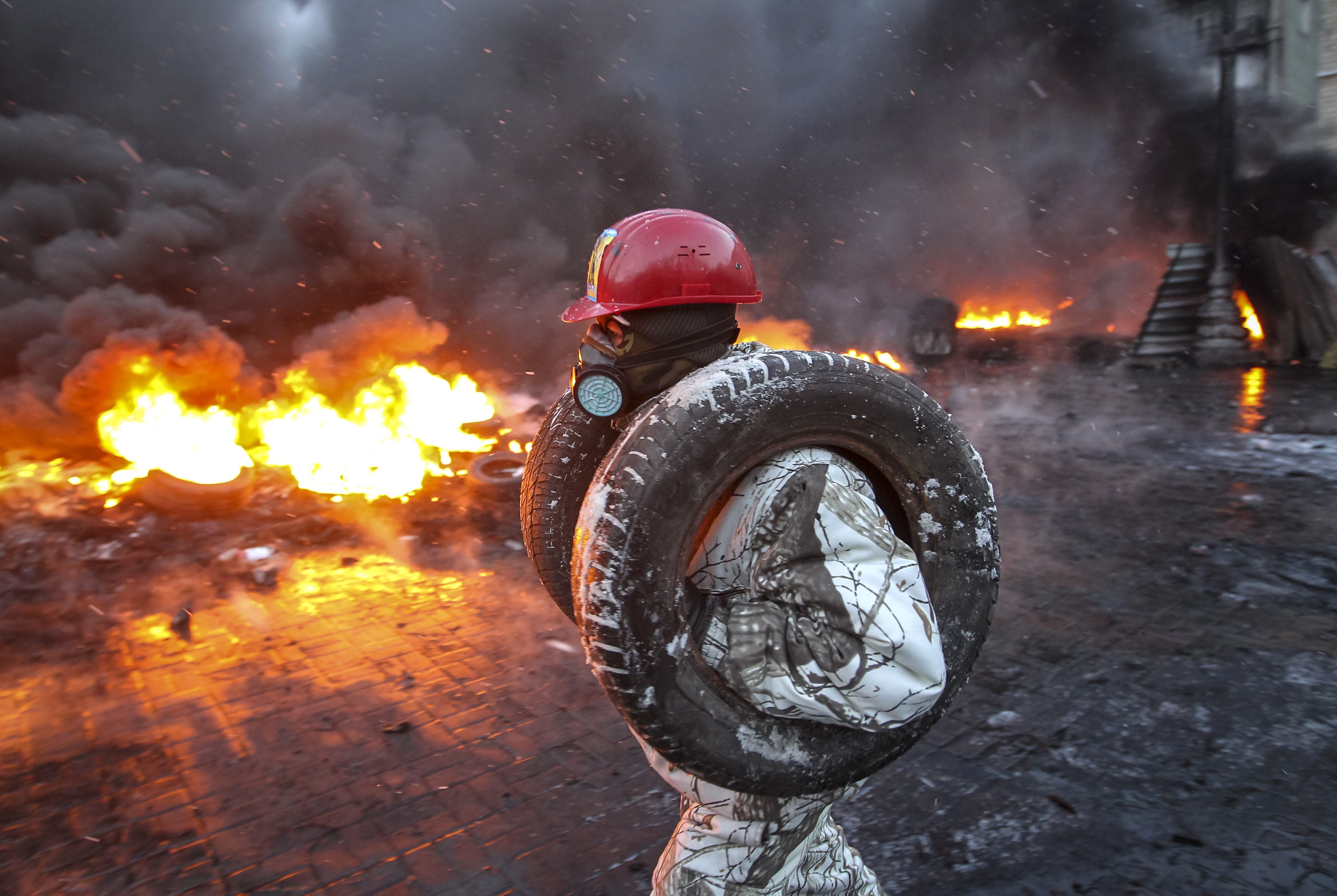 A pro-European integration protester carries tyres for burning at the site of clashes with riot police in Kiev January 23, 2014. Ukrainian opposition leaders emerged from crisis talks with President Viktor Yanukovich on Wednesday saying he had failed to give concrete answers to their demands, and told their supporters on the streets to prepare for a police offensive. REUTERS/Valentyn Ogirenko (UKRAINE - Tags: POLITICS CIVIL UNREST)